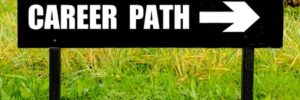 Black sign with "Career Path" and a white arrow pointing right, placed outdoors on a grassy area.