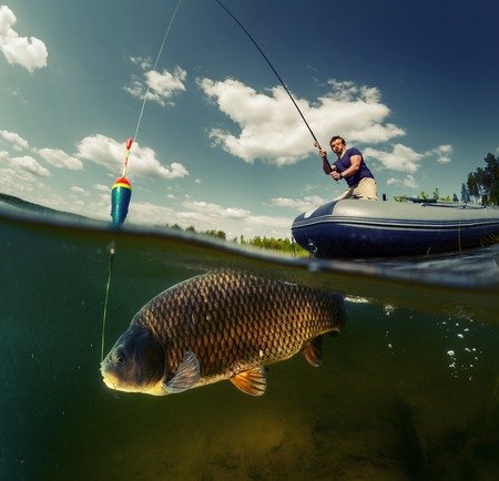 A man on an inflatable boat is fishing, with a large fish and a colorful float visible underwater.