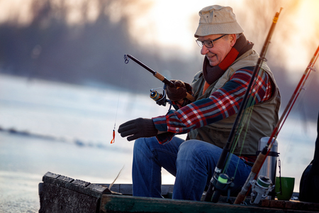 man fishing on frozen lake in the winter