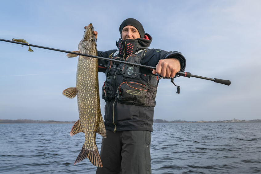 Happy fisherman holding his trophy pike catch