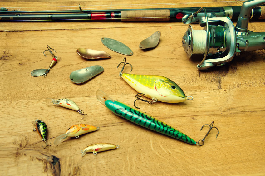 Fishing baits and rod isolated on wooden background
