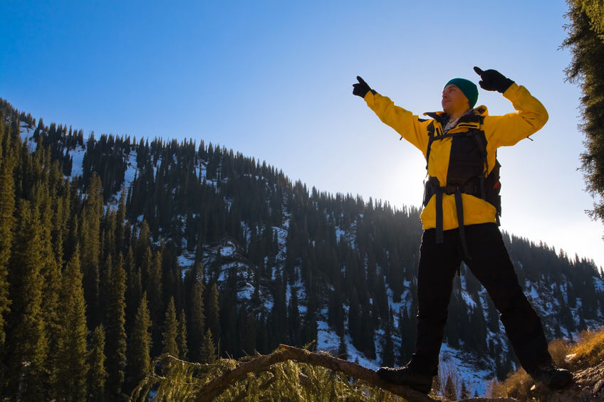 Climbing young adult man at the top of summit with aerial view of blue sky and mountain